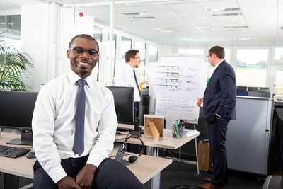 Mitarbeiterportrait mit Team im Hintergrund